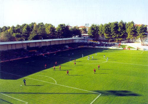 Vista del terreno de juego desde la grada durante un partido, con los jugadores sobre el césped.